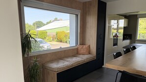 Une cuisine moderne avec un banc intégré, une table à manger et une vue sur l’extérieur.
