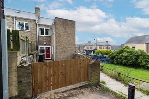 A residential area with brick houses, a wooden fence, and a paved path.