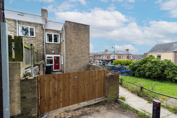 Un quartier résidentiel avec des maisons en briques, une clôture en bois et un chemin pavé.