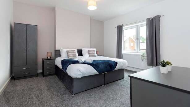 A modern bedroom with a bed, bedside tables, a wardrobe, and a window with curtains.