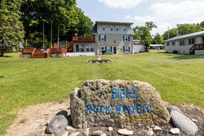 Uma área residencial com uma casa grande, um deck de madeira e uma rocha com a inscrição 'BIER'S ROCK HAVEN'.