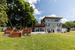 Une maison à deux étages dotée d’une terrasse en bois et d’un escalier menant à l’étage supérieur.