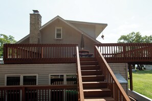 Une maison à deux étages dotée d’une terrasse en bois et d’un escalier.