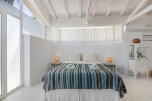 Un dormitorio con cama, lámparas de noche, un ventilador y un armario.
