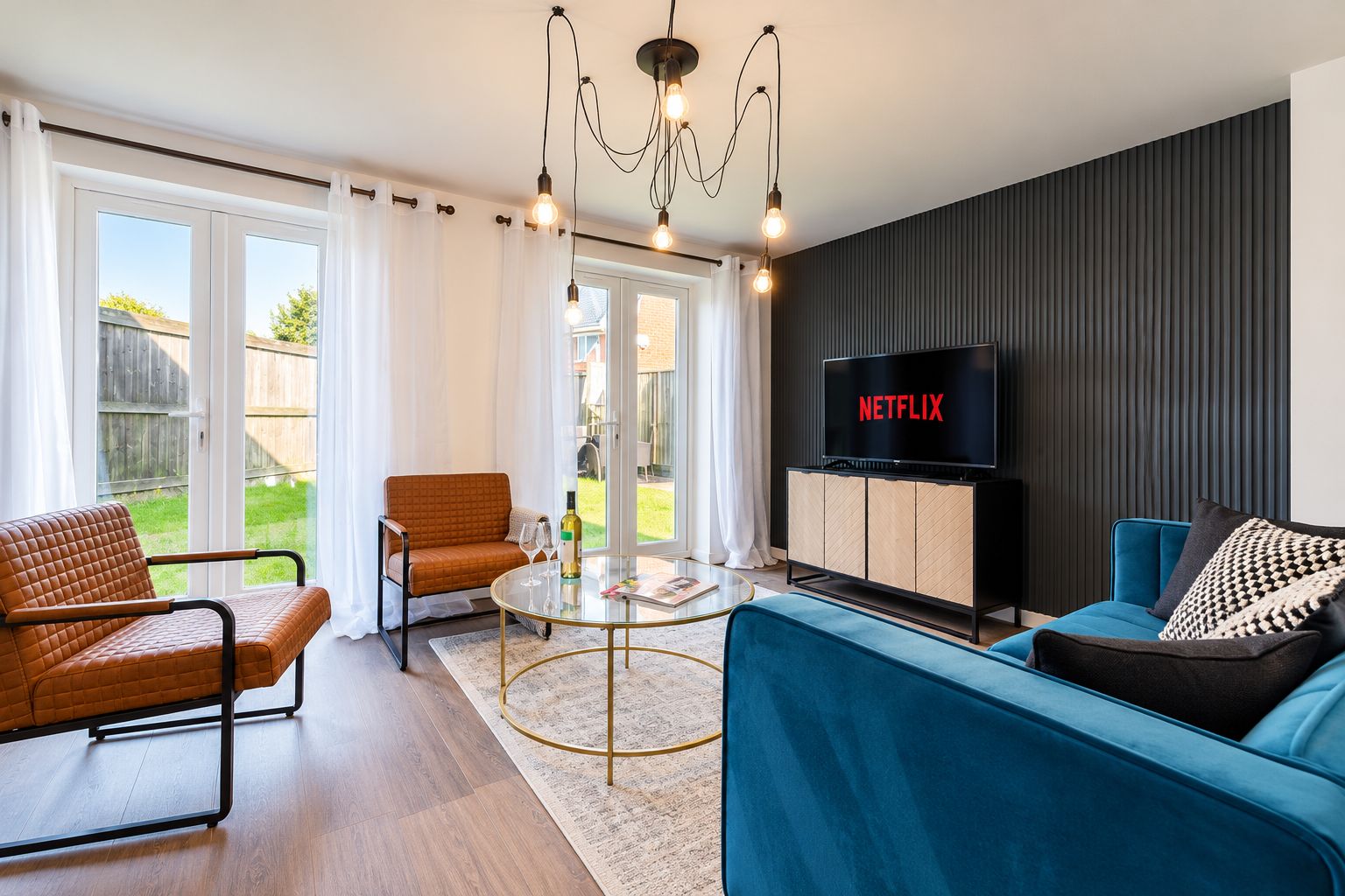 A modern living room with a sofa, armchair, and a glass coffee table.