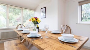 A dining table set with white plates, bowls, and cutlery, a vase with flowers, and a wine bottle. - Hot Tub/ Free Parking/ 5 Bedroom/ Large Space (Low Coniscliffe)