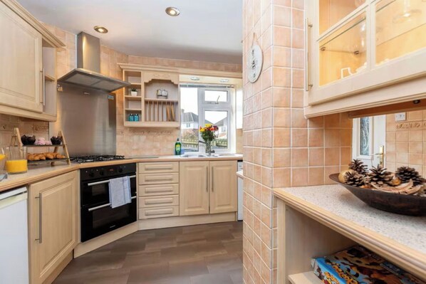 A modern kitchen with a gas stove, oven, and a window with a view.