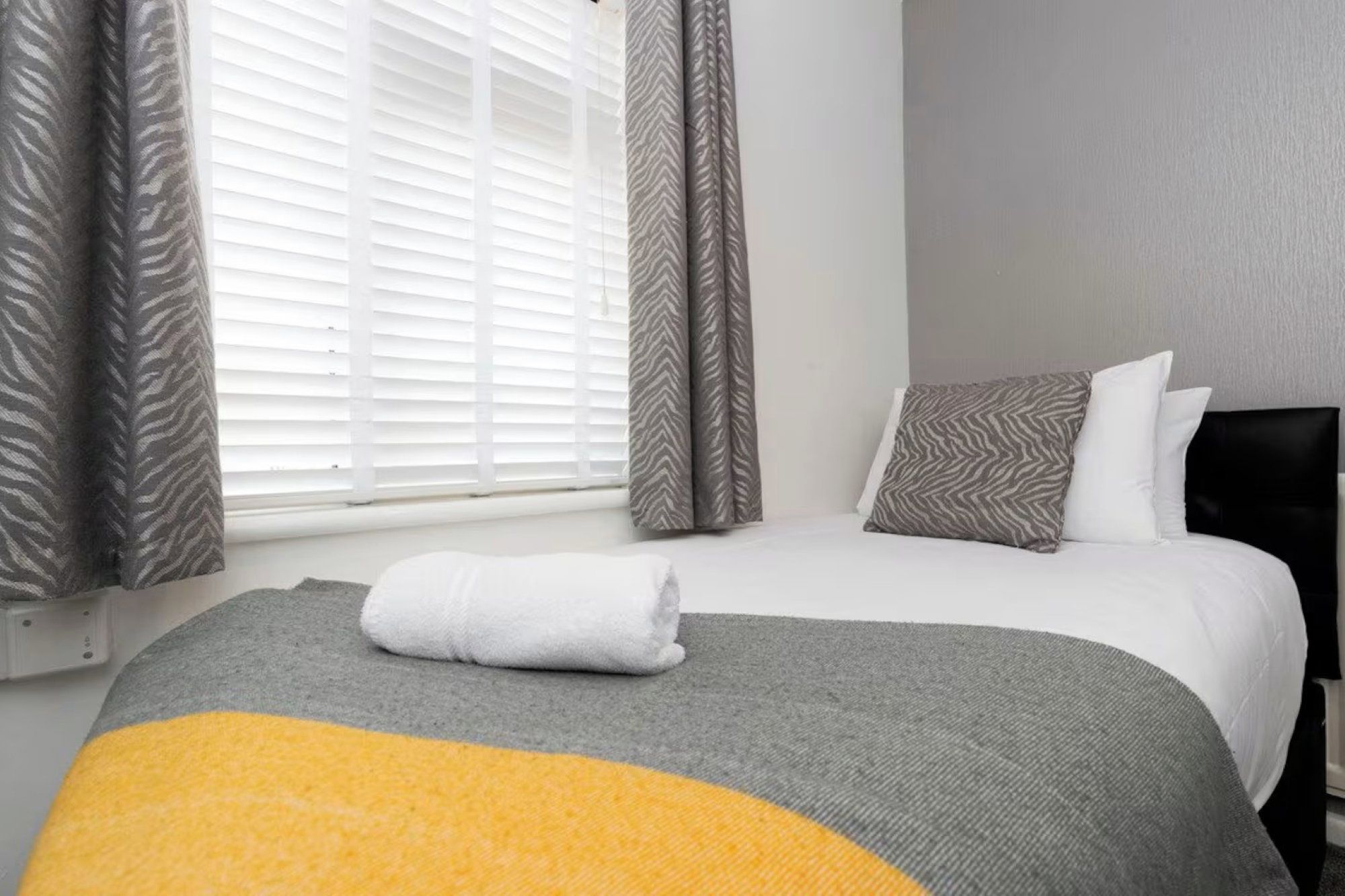 Habitació d'hotel amb un llit, una finestra amb persianes i cortines.