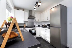 A modern kitchen with white cabinets, a stainless steel refrigerator, and a black countertop. - *Discounts/Contractors/WIFI/Free Parking/Smart TV (Gateshead)