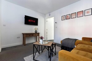 A living room with a TV, a small table with a vase, a sofa, and a door. - *Discounts/Contractors/WIFI/Free Parking/Smart TV (Gateshead)