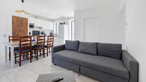 A modern living room with a grey sofa, wooden dining table, and chairs. - Family Home for 6–8 Guests with Heated Pool in Vendée! (Commequiers)