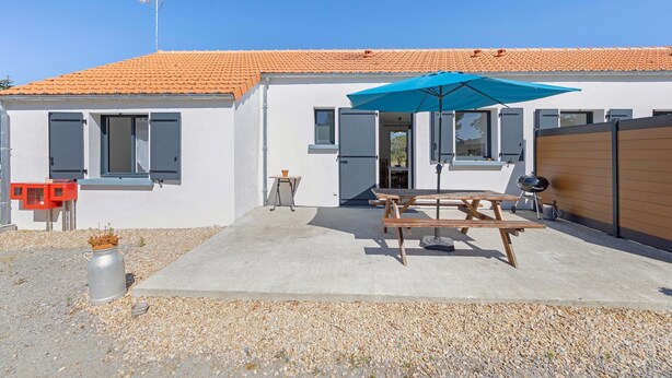 A house with a tiled roof, a patio with a table and umbrella, and a small garden area. - Family Home for 6–8 Guests with Heated Pool in Vendée! (Commequiers)