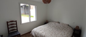 Une chambre à coucher avec un lit, une chaise, une fenêtre et un luminaire suspendu.