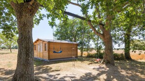 A wooden cabin with a swing set, surrounded by trees and a grassy field. - Family Home for 6–8 Guests with Heated Pool in Vendée! (Commequiers)