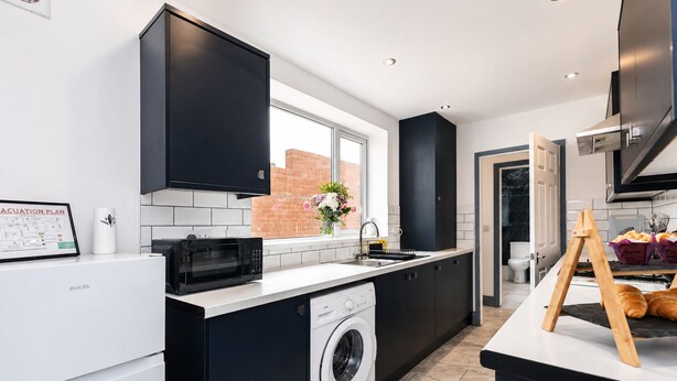 Een moderne keuken met een wasmachine, een magnetron en een spoelbak.