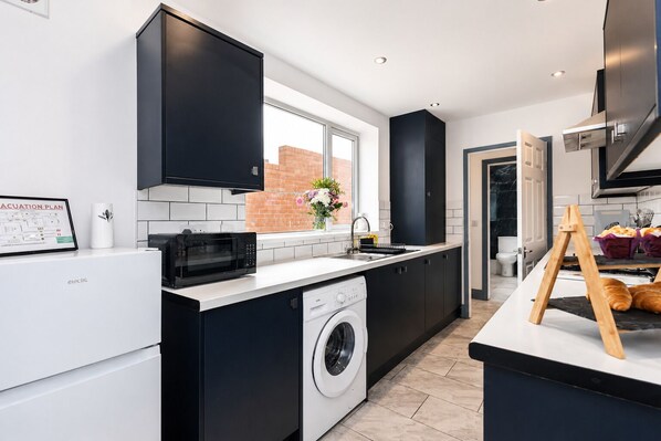 A modern kitchen with a washing machine, a microwave, and a sink. - Modern 4BR Contractor Stay in Darlington (Darlington)