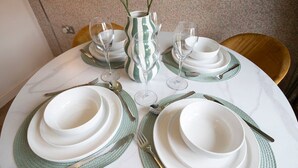 Une table ronde dressée avec de l’argenterie blanche, des sets de table verts et de la verrerie transparente.