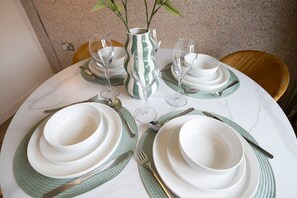 Una mesa redonda dispuesta con platos blancos, caminos de mesa verdes y cristalería transparente.