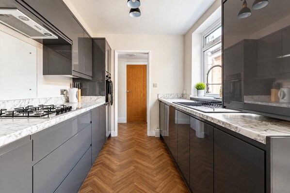 Una cocina moderna con suelo de madera en espiga, electrodomésticos de acero inoxidable y encimera de mármol.