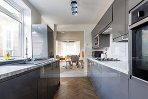 Eine moderne Küche mit dunklen Schränken, einer Marmorarbeitsplatte und Blick in den Essbereich.