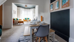 A dining area with a table set for four, a gray chair, and a blackboard wall. - 4BR Contractor Stay | Parking, Wi-Fi, Spacious (Sunderland)