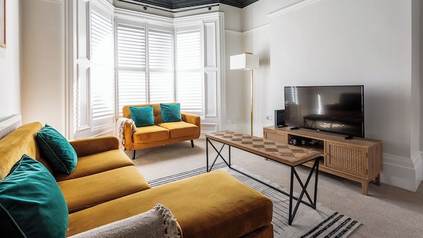 A living room with a sofa, a television, and a coffee table. - 4BR Contractor Stay | Parking, Wi-Fi, Spacious (Sunderland)
