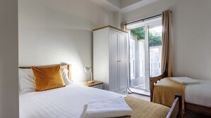 A hotel room with two beds, a wardrobe, a window with a view, and a bedside table with a lamp. - 4BR Contractor Stay | Parking, Wi-Fi, Spacious (Sunderland)