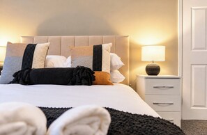Ein Hotelzimmer mit einem Bett, einem Nachttisch mit Lampe und einer Tür.