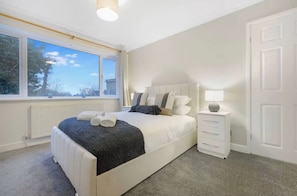 A bedroom with a bed, bedside table, and a view of the outdoors. - Modern 2BR | Middlesbrough | Parking (Normanby)
