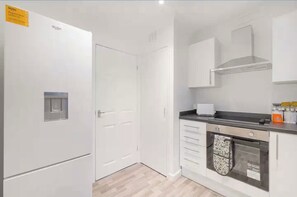 A kitchen with white cabinets, a built-in oven, and a microwave. - Modern 2BR | Middlesbrough | Parking (Normanby)