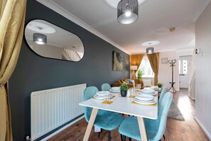 A dining area with a white table, teal chairs, and a mirror on the wall. - Stylish 3BR | Contractor Friendly | Long Stays (Bearpark)