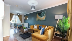 Uma sala de estar com sofá, mesa de centro e área de jantar com cadeiras e mesa.