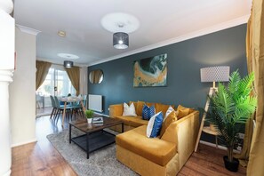 A living room with a sofa, coffee table, and a dining area with chairs and a table. - Stylish 3BR | Contractor Friendly | Long Stays (Bearpark)
