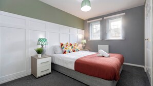 Quarto com cama, mesas de cabeceira, luminária e janela.