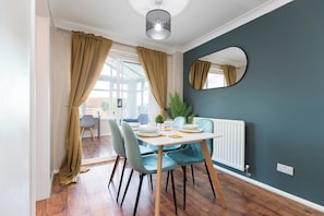 A dining area with a table set for four, a radiator, a mirror, and a view of the outside. - Stylish 3BR | Contractor Friendly | Long Stays (Bearpark)