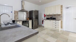 A modern kitchen with a stainless steel range, a built-in oven, a refrigerator, and white cabinetry. - Durham 5BR | Contractors & Long Stay Discounts (Murton)