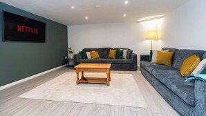 A living room with two sofas, a coffee table, a TV, and a lamp. - Durham 5BR | Contractors & Long Stay Discounts (Murton)