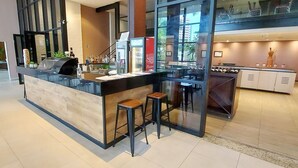 A modern bar area with a counter, stools, and a refrigerator stocked with beverages. - COCAR0116 - Boulevard Side Residencial (Salvador)