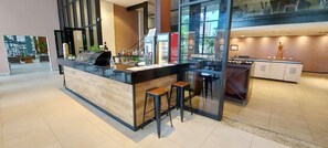 A modern bar area with a counter, stools, and a refrigerator stocked with beverages. - COCAR0116 - Boulevard Side Residencial (Salvador)