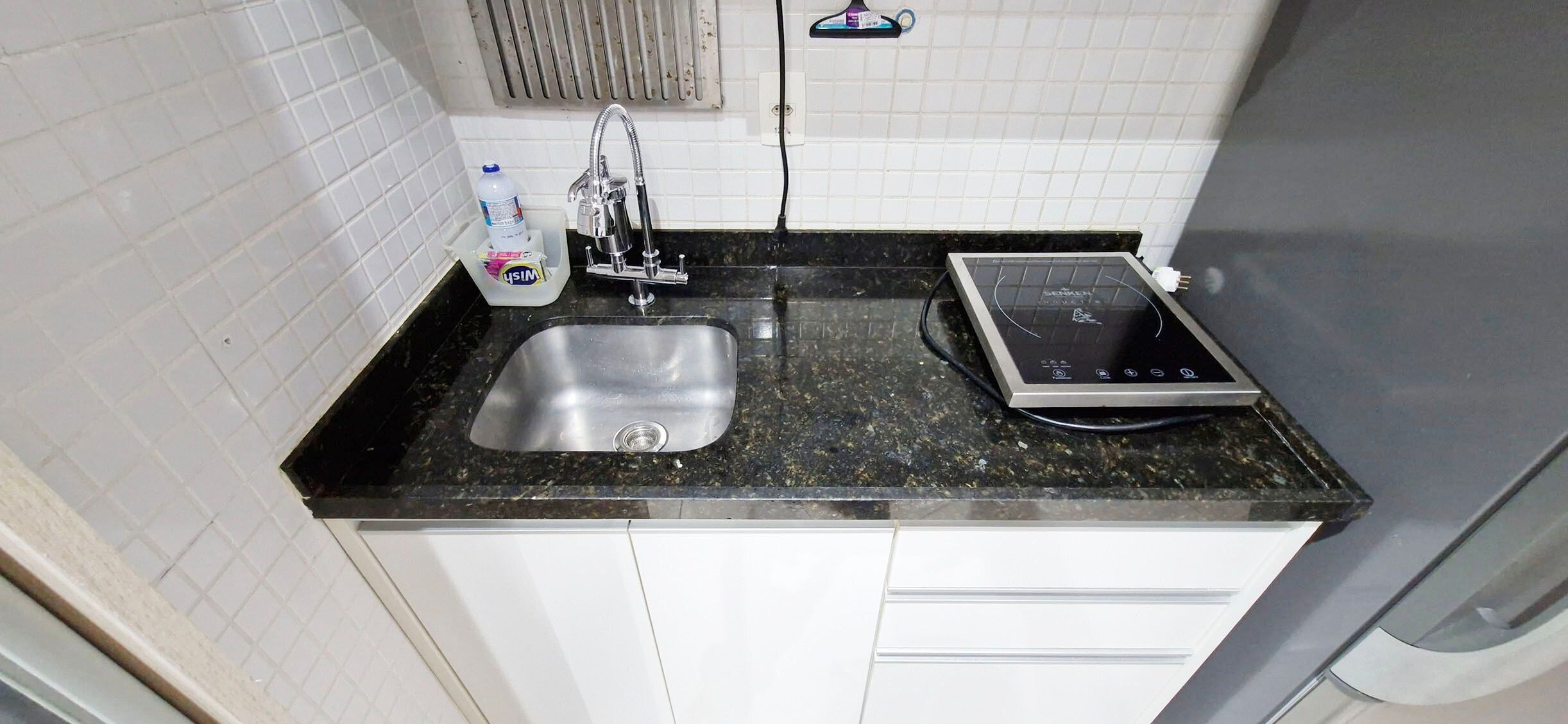 A kitchen with a stainless steel sink, a built-in electric stove, and a water dispenser.