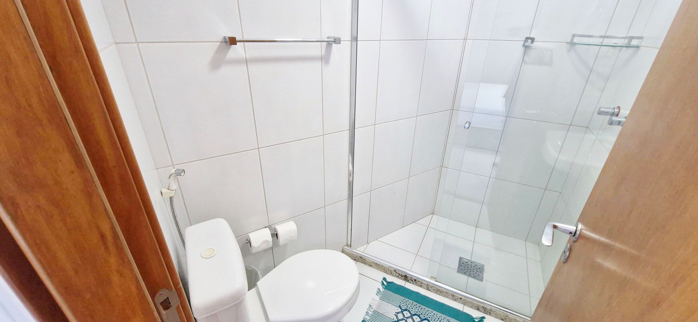 A bathroom with a toilet, a glass shower enclosure, and a tiled floor.
