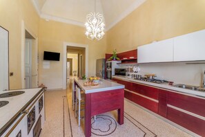 Una cocina con una isla central, una araña y un televisor montado en la pared.