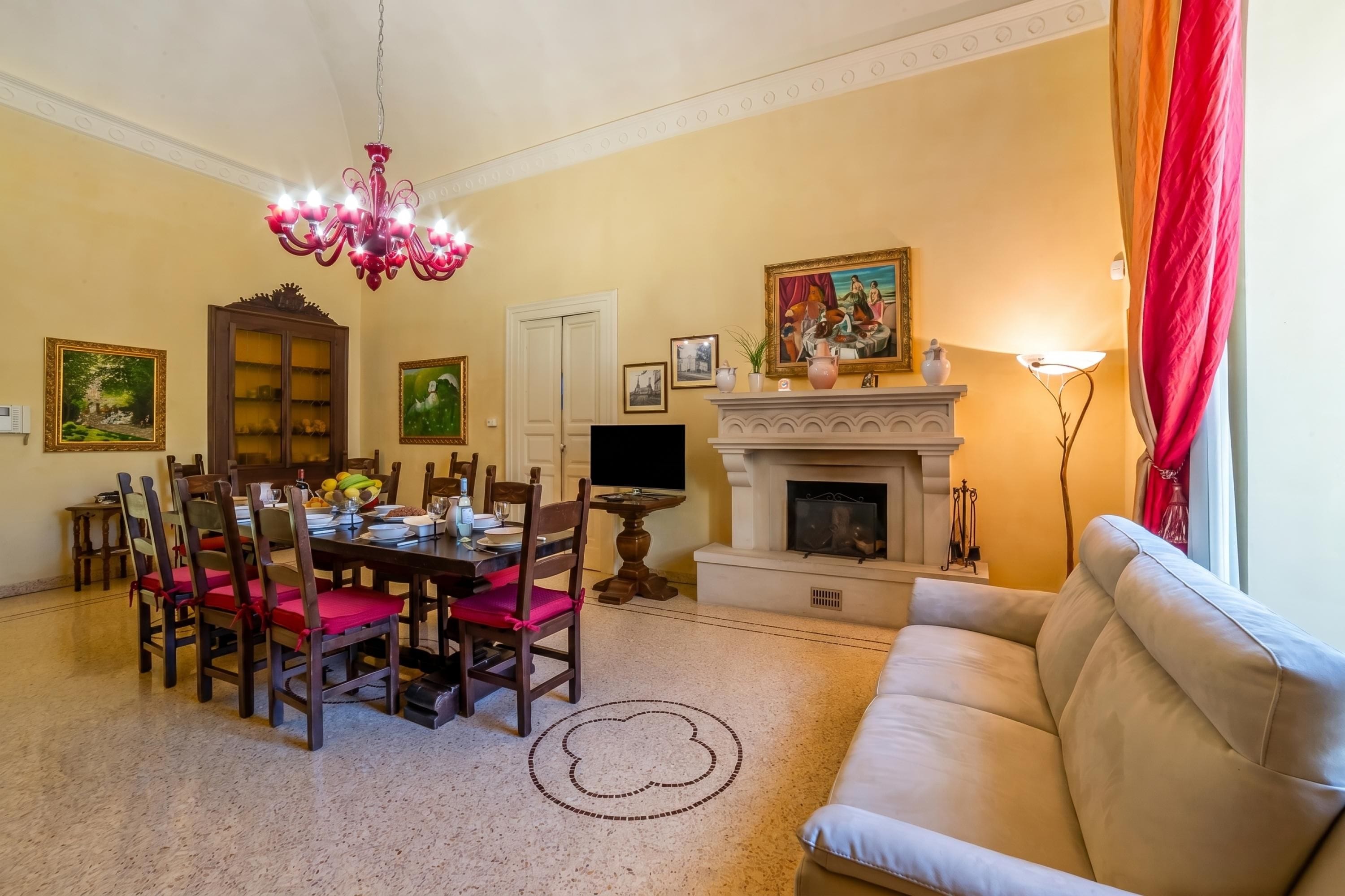 A dining area with a chandelier, a fireplace, and a sofa.