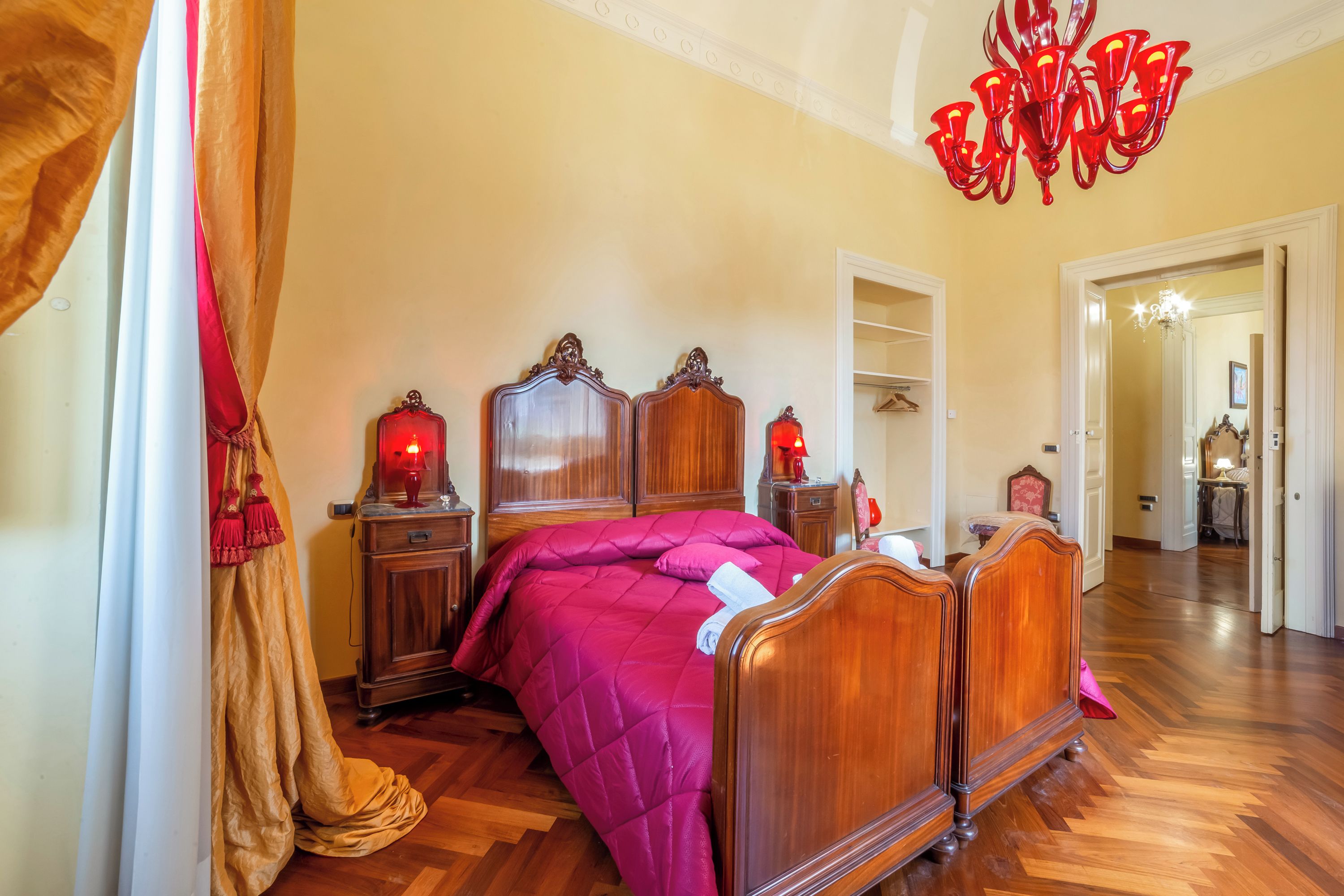 Ein Schlafzimmer mit einem hölzernen Bett, einer roten Chandelier und Holzboden.