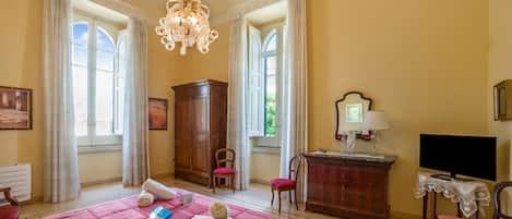Una habitación de hotel con cama, escritorio, silla, televisor y candelabro.