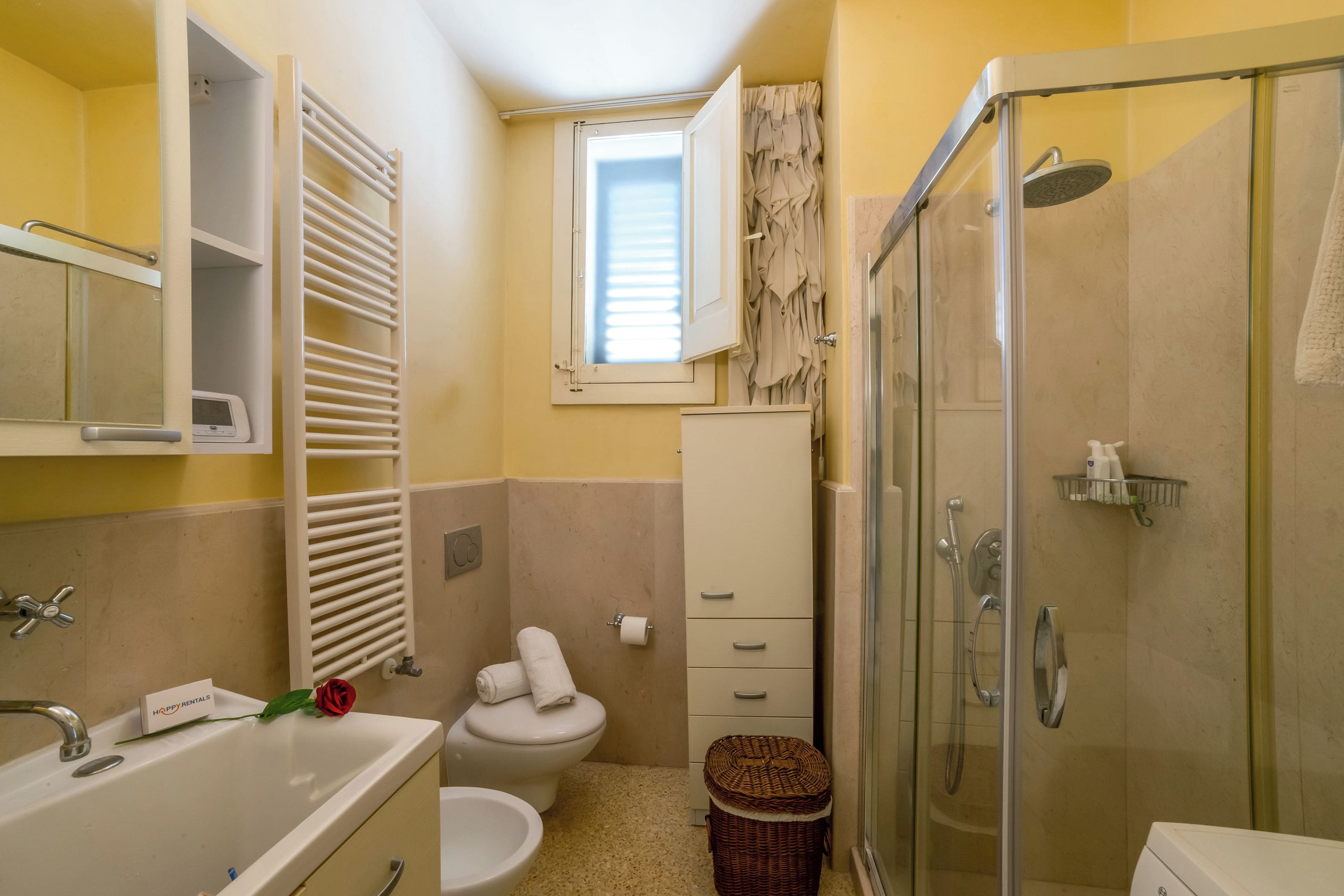 Ein Badezimmer mit Dusche, Toilette, Waschbecken und einem kleinen Fenster.