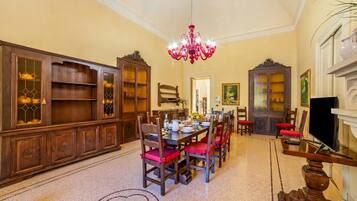 Un comedor con candelabro, armarios de madera y sillas rojas.