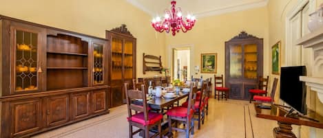 Un comedor con candelabro, armarios de madera y sillas rojas.