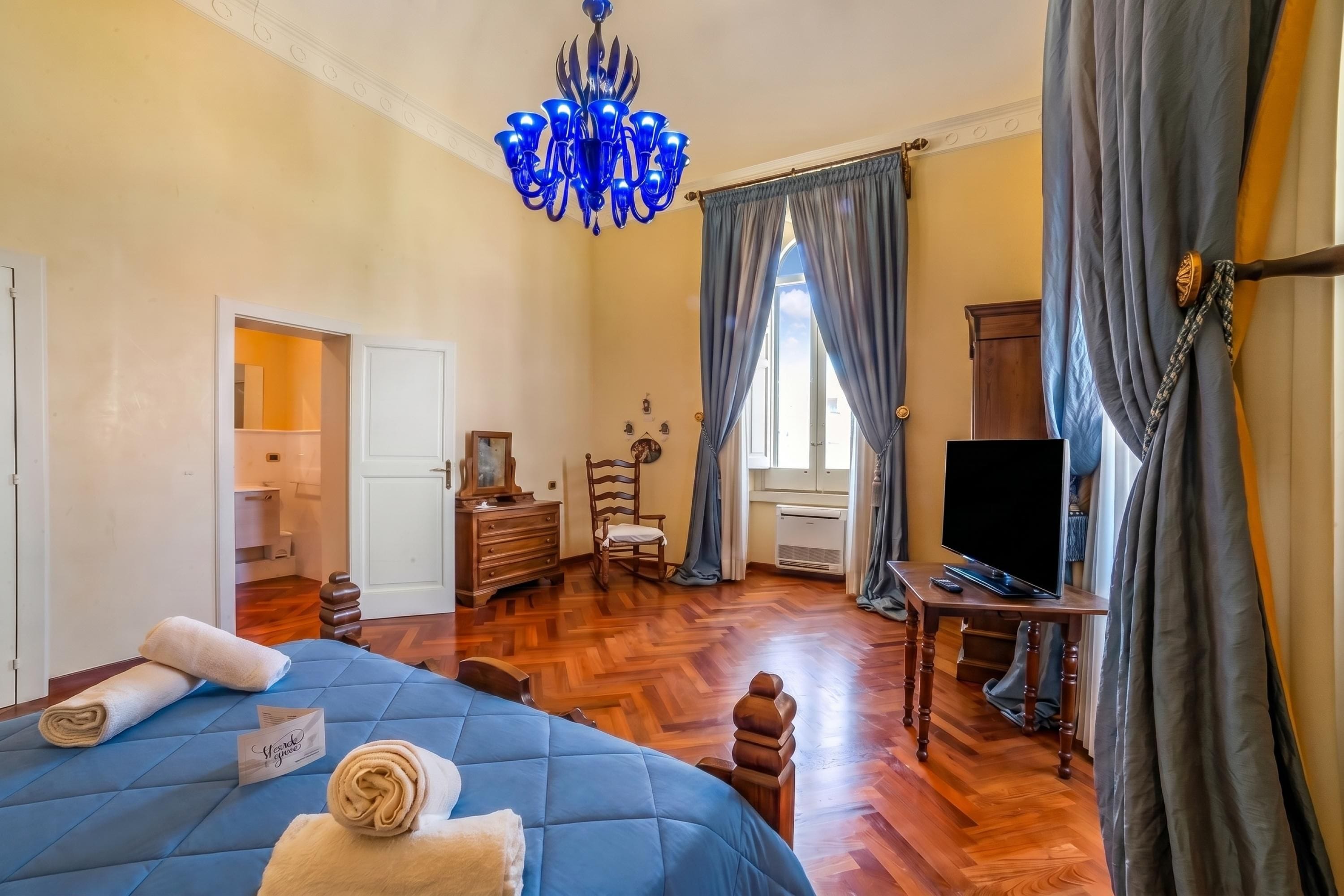 Une chambre à coucher comprenant un lit, une télévision, une commode et un lustre.