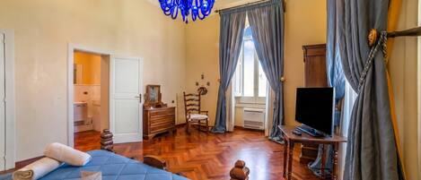 Un dormitorio con cama, televisión, cómoda y candelabro.